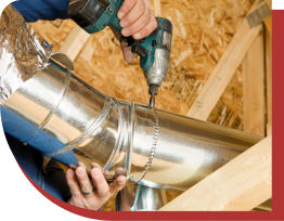 Someone using an electric drill to install ductwork in a home