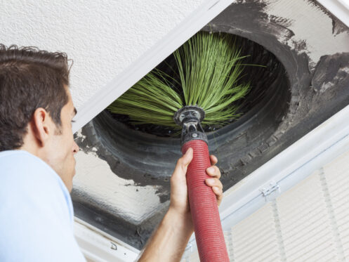Man cleaning air ducts in a Sarasota home.